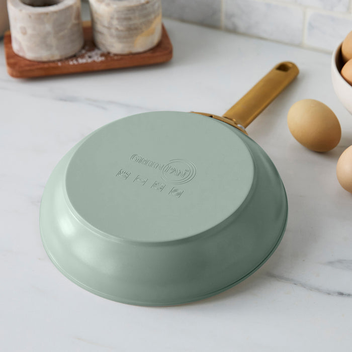 Green frying pan with a gold handle on a kitchen counter