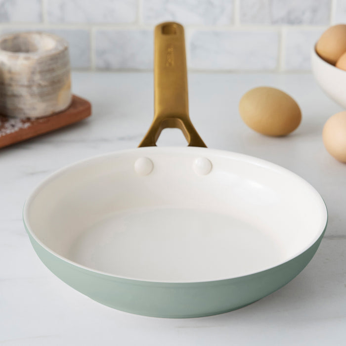 Green frying pan with a cream interior on a kitchen counter.