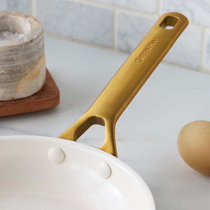 Green frypan with a gold handle on a kitchen counter