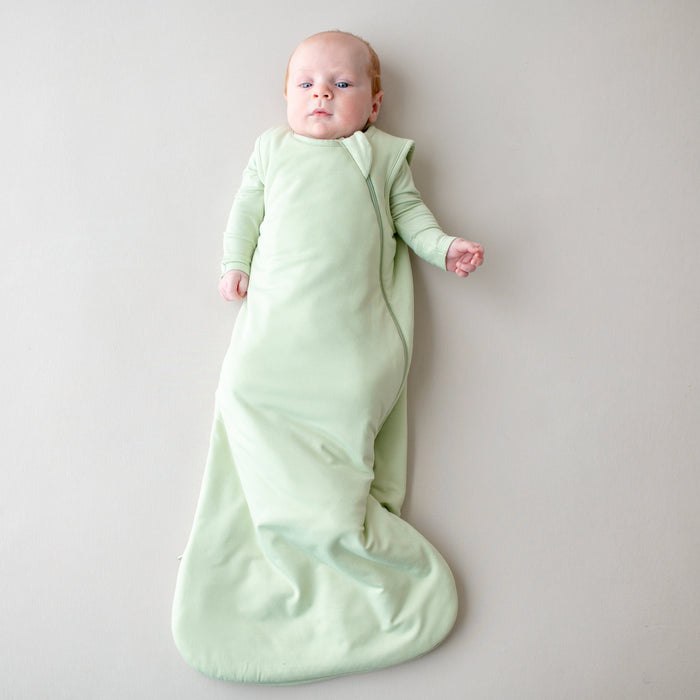 Baby in a 1.0 tog sleep bag in a light green color