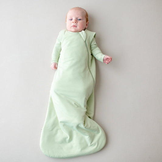 Baby in a 1.0 tog sleep bag in a light green color
