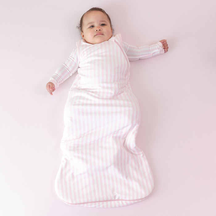 Infant laying on a pink blanket wearing the soft and breathable Sleep Bag in Small Sakura Stripe 1.0 and matching romper