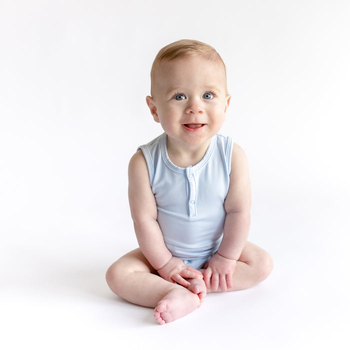 Young toddler sitting on the floor wearing the Sleeveless Bodysuit in Breeze