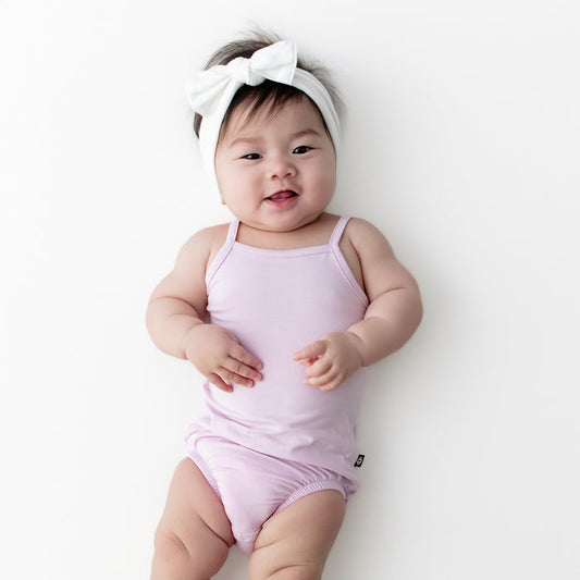 Infant girl wearing the Spaghetti Strap Leotard in Thistle with a white knotted bow