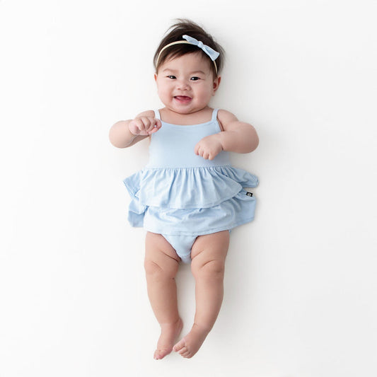 Infant wearing the Spaghetti Strap Ruffle Romper in Breeze with matching tiny nylon bow