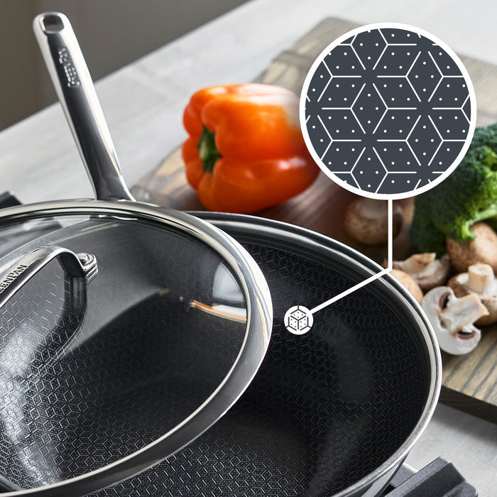 Hybrid ceramic nonstick wok with lid, featuring a geometric design; vegetables on a cutting board in the background.