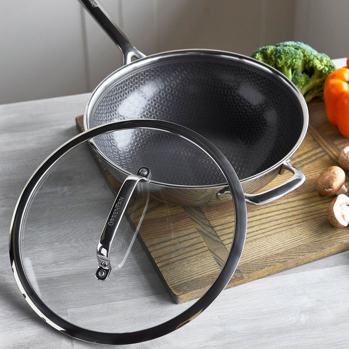 Hybrid ceramic nonstick 12-inch wok with lid on wooden board, surrounded by fresh vegetables.