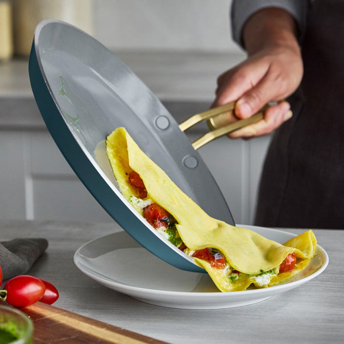 Person releasing a crepe from a pan onto a plate