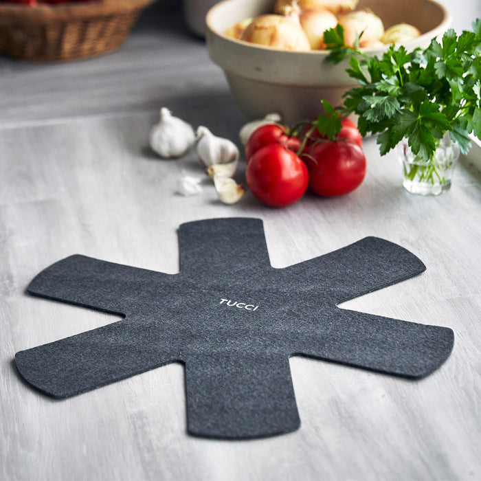 Black felt pan protector with TUCCI text next to fresh herbs, designed for a single large frypan.