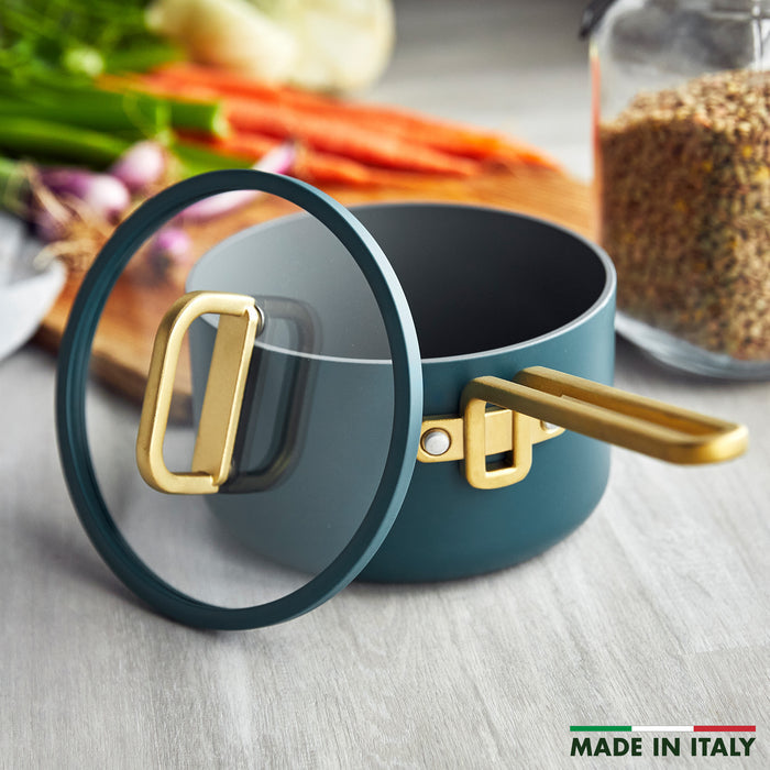 Venetian teal ceramic 2-quart saucepan with gold handle, shown next to assorted vegetables.
