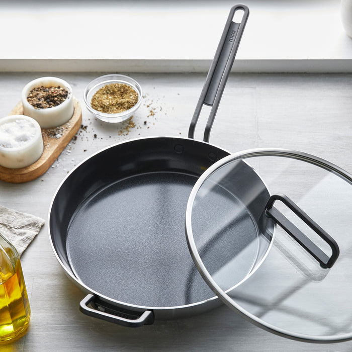 12-inch stainless steel ceramic nonstick frypan with lid on countertop, near spices and olive oil.