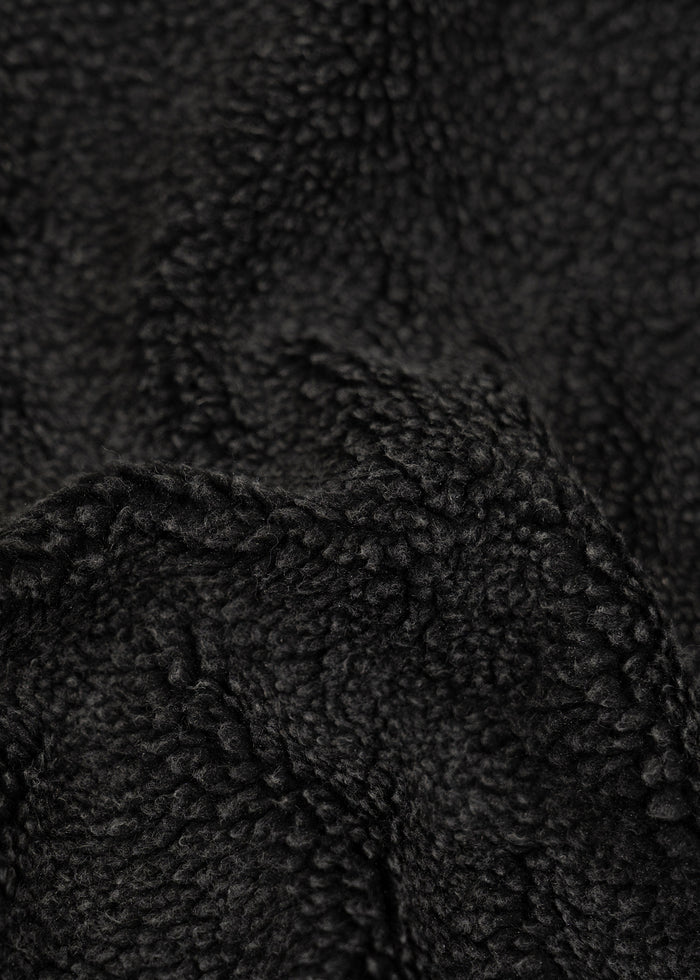 Close-up of black fleece fabric texture, showing soft, curly fibers and a cozy, warm appearance.