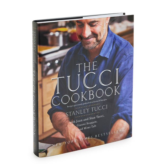 The Tucci Cookbook cover showing a smiling man cooking in a kitchen with Italian dishes on the counter.