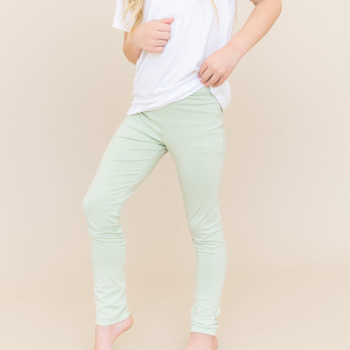 Close up of a young girl wearing the Toddler Leggings in Basil