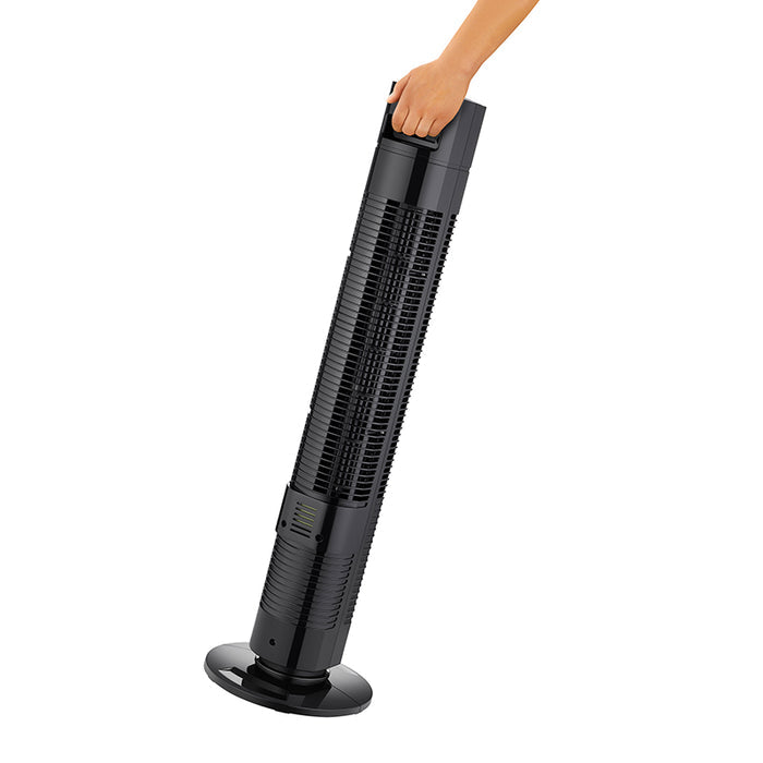 Eine Hand hält den oberen Griff des Unold TURMVENTILATOR TORRE und kippt den schlanken, vertikalen schwarzen Turmventilator mit kreisförmigem Standfuß, als würde sie ihn bewegen oder tragen.