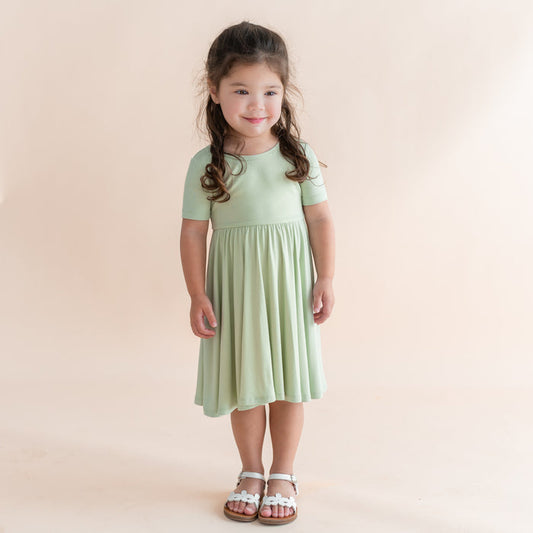 Young girl wearing a light green dress against a beige background