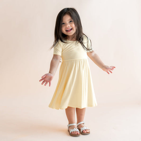 Child wearing a light yellow short sleeve twirl dress