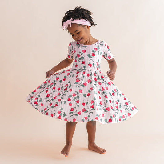 Young girl twirling in the light and airy Twirl Dress in Strawberry Fields