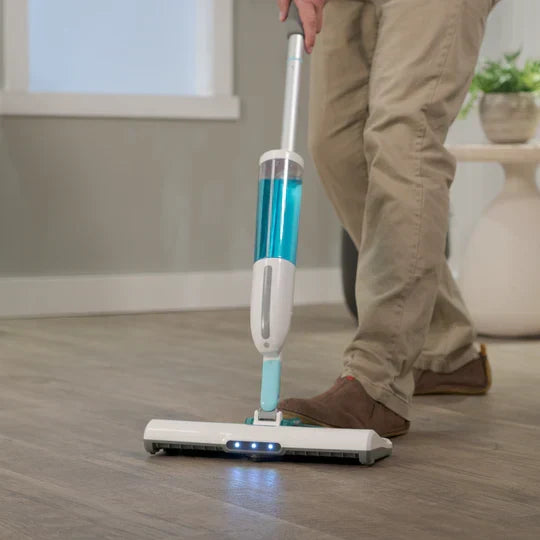 Person using a cordless floor cleaning device on a wooden floor.